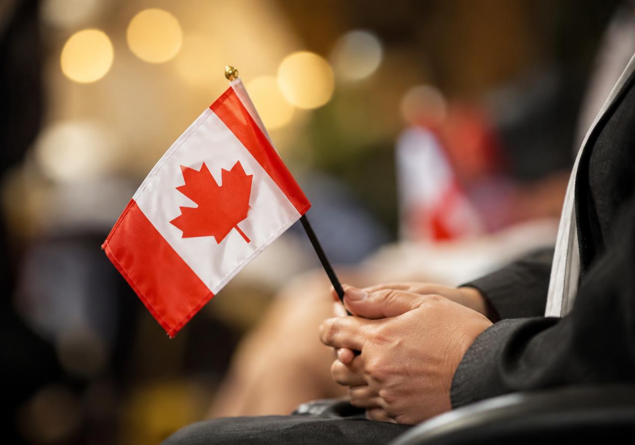 Hands holding a small Canadian flag at a citizenship ceremony